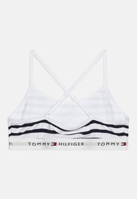 Bijela braletica s mornarskim prugama, leđa s ukrštenim trakama i elastičnom trakom s oznakom "TOMMY HILFIGER" u crvenoj i mornarskoj boji.