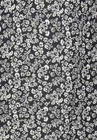 Marine stof met een wit bloemenpatroon, gekenmerkt door ingewikkelde bladeren en bloemen, wat een delicate, textuurrijke uitstraling creëert.