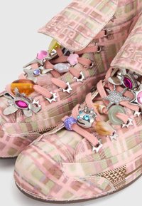 Ροζ καρό sneakers με ψηλή μύτη, διακοσμημένα με πολύχρωμα χάντρινα γούρια και ασημένιες οπές σε σχήμα αστεριού στα κορδόνια.