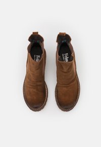 Bottines en suède marron avec une finition lisse, des panneaux latéraux élastiques et des coutures contrastées. L'intérieur est doté d'une doublure en textile à motifs.