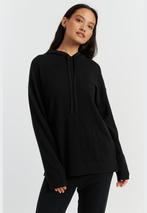 Sweater nero con cappuccio, maniche lunghe, polsini a costine e vestibilità rilassata. Realizzato in materiale morbido, presenta un design semplice e pulito.
