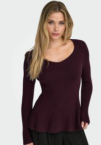 Maglione bordeaux a coste con scollo a V, maniche lunghe e orlo svasato. Realizzato in tessuto strutturato, offre una silhouette aderente.