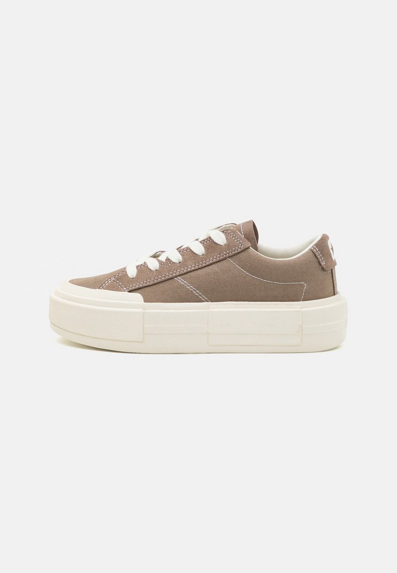 Baskets en toile marron avec lacets blancs, semelle en caoutchouc surélevée et détails de couture. Présentent une texture lisse et un design à bout rond.