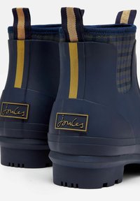 Granatowe gumowe botki za kostkę z teksturowanym wzorem, z dodatkami w kolorze złotym i kontrastującymi paskami do łatwego zakładania.