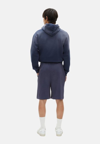 Marineblauwe hoodie met een trekkoord en kangoeroezak, gecombineerd met bijpassende shorts. Glad textuur, comfortabele pasvorm en zachte stof.