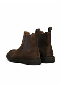 Stivaletti Chelsea in suede marrone con pannelli elastici e linguette posteriori, caratterizzati da una suola piatta in gomma nera e un rivestimento interno morbido.
