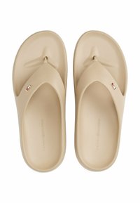 Beige gummiflip-flops med en bred rem, der har et subtilt logo og en struktureret sål for bedre greb. Glatte overflader med minimalistisk design.