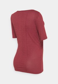 Tunic rossa a coste con maniche corte, caratterizzata da una scollatura arrotondata e spacchi laterali per facilitare i movimenti. Tessuto morbido e texturizzato.