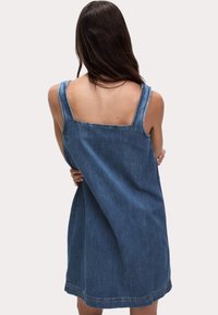 Sukienka dżinsowa o prostym kroju, niebieskiego koloru, z szerokimi ramiączkami i kwadratowym dekoltem. Charakteryzuje się surowymi krawędziami i długością do połowy uda.