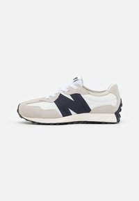 Lys grå sneaker med mørkeblå detaljer og hvit panelering. Har en teksturert semsket overdel, snøring og gummisåle.