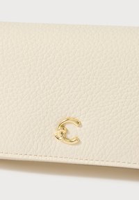 Cream-colored leather wallet with a textured finish, featuring a gold-tone logo accent and visible stitching detail.