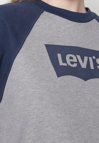 Sudadera de Levi's con cuerpo gris y mangas en color marino. Presenta un gran gráfico del logo en color marino en la parte frontal, hecho de una suave mezcla de algodón.
