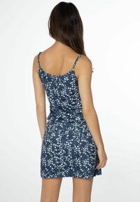 Granatowa sukienka w kwiaty z białymi wzorami, regulowane ramiączka, dopasowany krój i lekko rozkloszowany dół.