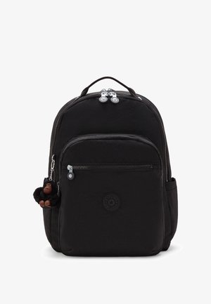 Sac à dos noir en tissu texturé, avec double zip, poche avant et un porte-clés en forme de singe. Il présente un logo de marque circulaire à l'avant.