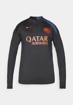 Svart langermet sportsskjorte med halv glidelås i kragen, med oransje "Qatar Airways"-logo og emblem på venstre bryst, samt blå skulderdetaljer.