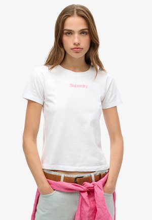Hvid bomulds t-shirt med et lyserødt "Superdry" logo. Korte ærmer, rund hals, afslappet pasform, parret med en lyserød knyttet sweater og lyse jeans.