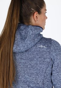 Felpa blu navy con tessuto a maglia testurizzata, caratterizzata da un cappuccio e un discreto logo di montagna. Il design è aderente con un taglio di lunghezza media.