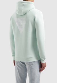 Vaaleanvihreä huppari, jossa on kiristysnyöri, resorit hihansuissa ja valkoinen kolmionmuotoinen raidallinen kuvio selässä. Pehmeä puuvillasekoitekangas.