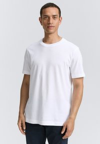 Weißes T-Shirt mit kurzen Ärmeln und Rundhalsausschnitt, aus glattem Stoff, mit lockerer Passform und subtiler Textur, vor einem neutralen Hintergrund präsentiert.