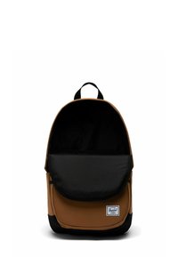 Sac à dos en tissu marron avec un rabat noir, doté d'une poche avant et d'une poignée supérieure. Présente un écusson logo en bas.