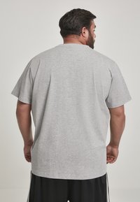 T-shirt gris à manches courtes en tissu mélangé de coton, avec une coupe décontractée et un ourlet droit, vu de dos.