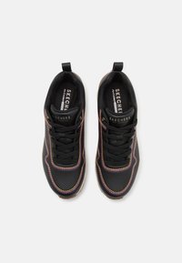 Chaussures de sport noires avec un col rembourré, dotées de coutures multicolores, de panneaux texturés et d'une semelle en caoutchouc. Lacets à l'avant.