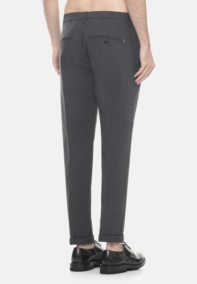 Pantaloni grigi su misura con taglio dritto, dotati di due tasche posteriori, orli arrotolati e una texture liscia. Indossati con scarpe nere stringate.