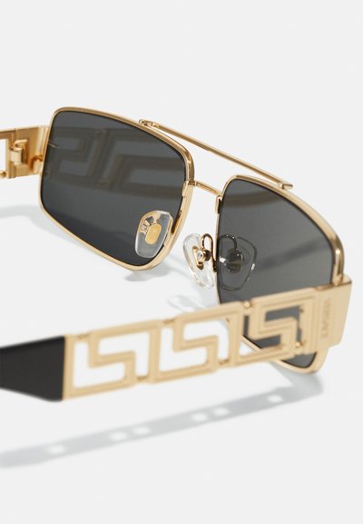 Ochelari de soare din metal aurit cu lentile închise, având un model geometric pe brațe și pad-uri clare pentru confort.