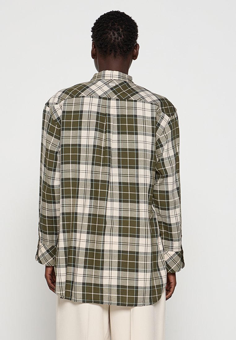 Camisa de cuadros verde y crema de manga larga con un ajuste relajado, yugo en la parte posterior y dobladillo curvado. Hecha de una tela ligera y tejida.