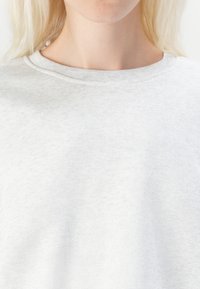 Felpa grigia chiara con collo rotondo a coste, realizzata in materiale morbido. Presenta una superficie texturizzata e un design slim-fit, senza motivi distintivi.