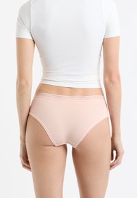 Jasnoróżowe bawełniane majtki o gładkiej fakturze, z elastycznym paskiem w talii ozdobionym subtelnym wzorem oraz prostym, klasycznym krojem.