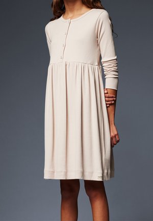 Dostosowana, długorękawowa sukienka w miękkim beżowym kolorze, z okrągłym dekoltem i detalem w postaci guzików; zwiewna spódnica z marszczonym materiałem w pasie.