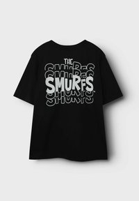 Camiseta de algodón negra de manga corta, con un texto en negrita de color blanco que dice "LOS PITUFOS" en varios estilos y tamaños en la parte de atrás.