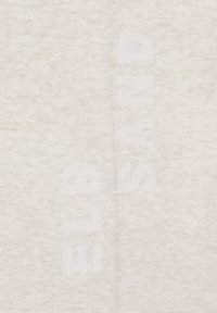 Cremefarbener Stoff mit einer weichen, strukturierten Oberfläche, auf der leicht sichtbare weiße Schriftzüge zu sehen sind. Das Design wirkt einfach und minimalistisch.