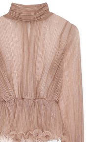 Gaiši rozā, pleitota blūze ar augstu apkakli, savilkta josta un volānu apakšmalu. Caurskatāms audums piešķir tekstūru un plūdenumu dizainam.