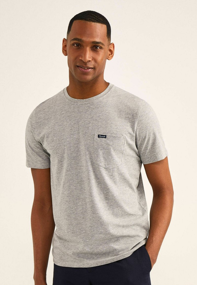 Grijze t-shirt met korte mouwen, gemaakt van zachte stof, voorzien van een voorzak met een donker etiket, ronde hals en een ontspannen pasvorm.