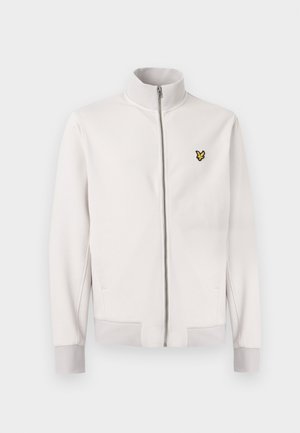 Λευκό μπουφάν με φερμουάρ και ψηλό γιακά, ριμπ μανσέτες και τελείωμα, με μικρό κίτρινο λογότυπο πουλιού στο αριστερό στήθος.