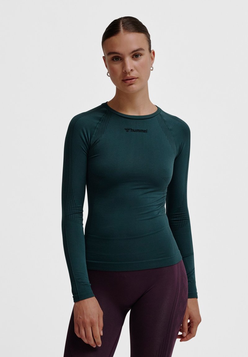 Donkergroene lange mouwen sporttop gemaakt van rekbare stof, met ergonomische naden, een ronde hals en subtiele textuurpatronen.