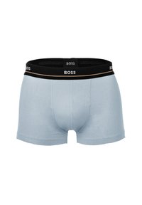 Caleçons boxers pour hommes en bleu clair avec une ceinture élastique noire portant le logo BOSS en blanc et une fine rayure beige.