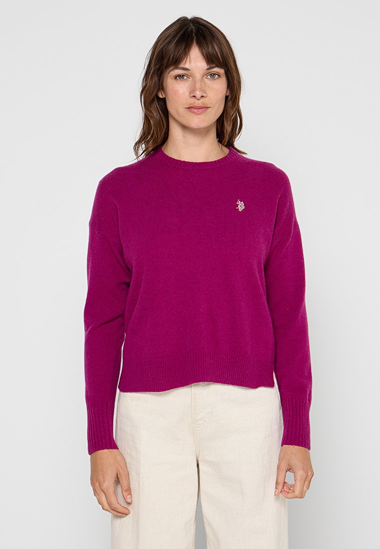 Magenta sweter z dzianiny o okrągłym dekolcie i ściągaczami, ozdobiony małym wyszywanym logo na lewej piersi oraz skróconym dołem.