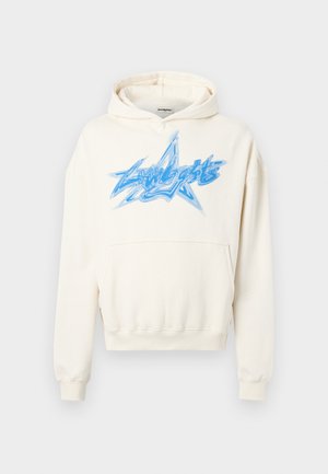 Sweat à capuche crème avec une poche avant, arborant un grand graphique d'étoile bleue avec du texte. Fabriqué en tissu doux avec une coupe décontractée et des poignets côtelés.