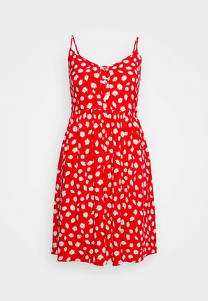 Robe rouge avec des bretelles spaghetti, devant à boutons, motif floral de marguerites blanches, taille froncée et jupe évasée.