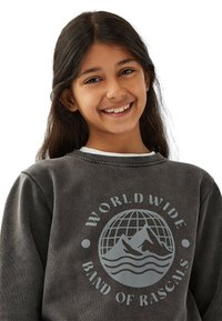 Tummanharmaa collegepaita, jossa on pyöreä grafiikka, jossa näkyy vuoria ja aaltoja, sekä tekstit "WORLD WIDE" ja "BAND OF RASCALS" vaaleanharmaalla. Yksinkertainen, pyöreä kaula-aukko.