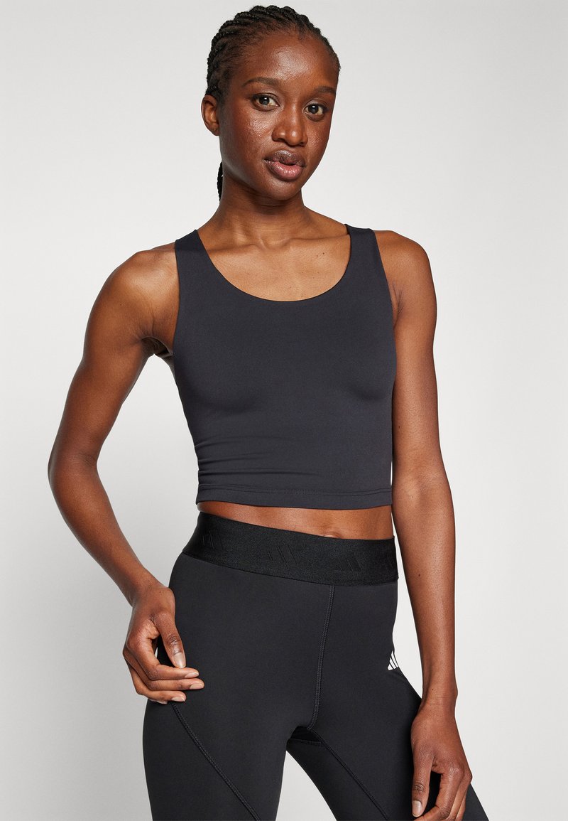 Débardeur noir raccourci avec un col rond et de larges bretelles, en tissu lisse et extensible. Assorti à des leggings noirs avec une taille texturée.