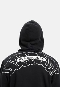 Felpa nera con cappuccio e grande testo grafico bianco sul retro, caratterizzato da lettere curve e il nome del marchio "DCSHOECUSA". Tessuto testurizzato, design con cappuccio.