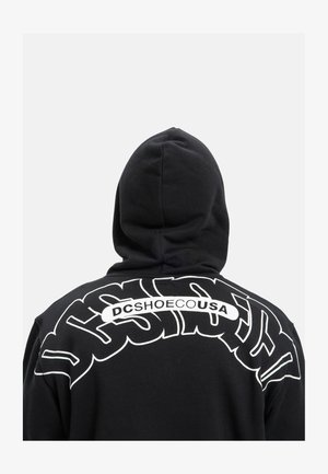Czarna bluza z kapturem z dużym białym tekstem graficznym na plecach, z zakrzywionymi literami i nazwą marki "DCSHOECUSA". Teksturowany materiał, projekt z kapturem.