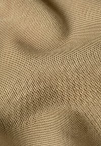 Tessuto a maglia beige con un motivo a costine texture, che mostra lievi variazioni di tonalità e una superficie liscia e morbida.