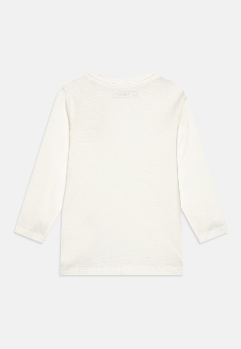 Chandail à manches longues, de couleur crème claire, fabriqué en coton doux. Il présente un col rond et une étiquette discrète à l'arrière, avec des coutures soigneusement finies.