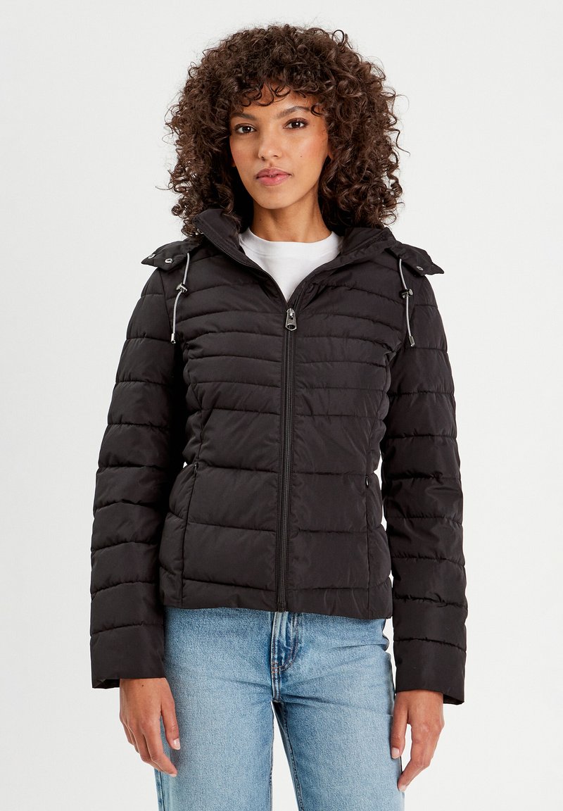 Veste matelassée noire avec fermeture éclair à l'avant, capuche réglable et poches latérales. Présente un design matelassé et une coupe courte. Texture lisse.