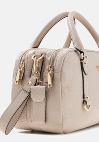 Beige leren handtas met textuur, dubbele handvatten, twee gouden ritsen en een afneembare riem met bijpassende leren sleutelhouder.